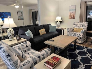 A modern living room with a sofa, armchairs, a coffee table, and a TV.