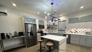 Une cuisine moderne dotée d’un réfrigérateur en acier inoxydable, d’un coin café et d’un tabouret de bar.