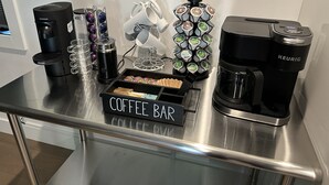 Un coin café aménagé avec une machine à café Keurig, une machine à café Nespresso, un porte-tasses et une boîte étiquetée  « BAR À CAFÉ ».