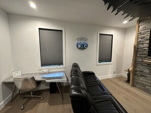 Et moderne kontor med skrivebord, læderstol og to vinduer med persienner.