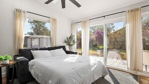 A bedroom with a bed, a ceiling fan, a window with curtains, and a view of the outdoors. - Beautiful summer open concept house that feels like home away from home, exceptionally clean with a great outdoor space and fire pit! Near speedway, airport, and beach! (Port Orange)