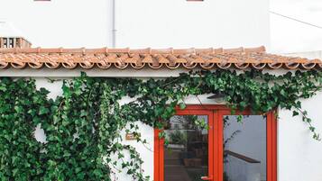 A building with a tiled roof, a red door, and a wall covered in green ivy.