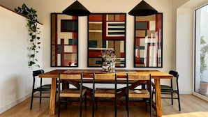 A dining area with a wooden table, black chairs, and three pendant lights.