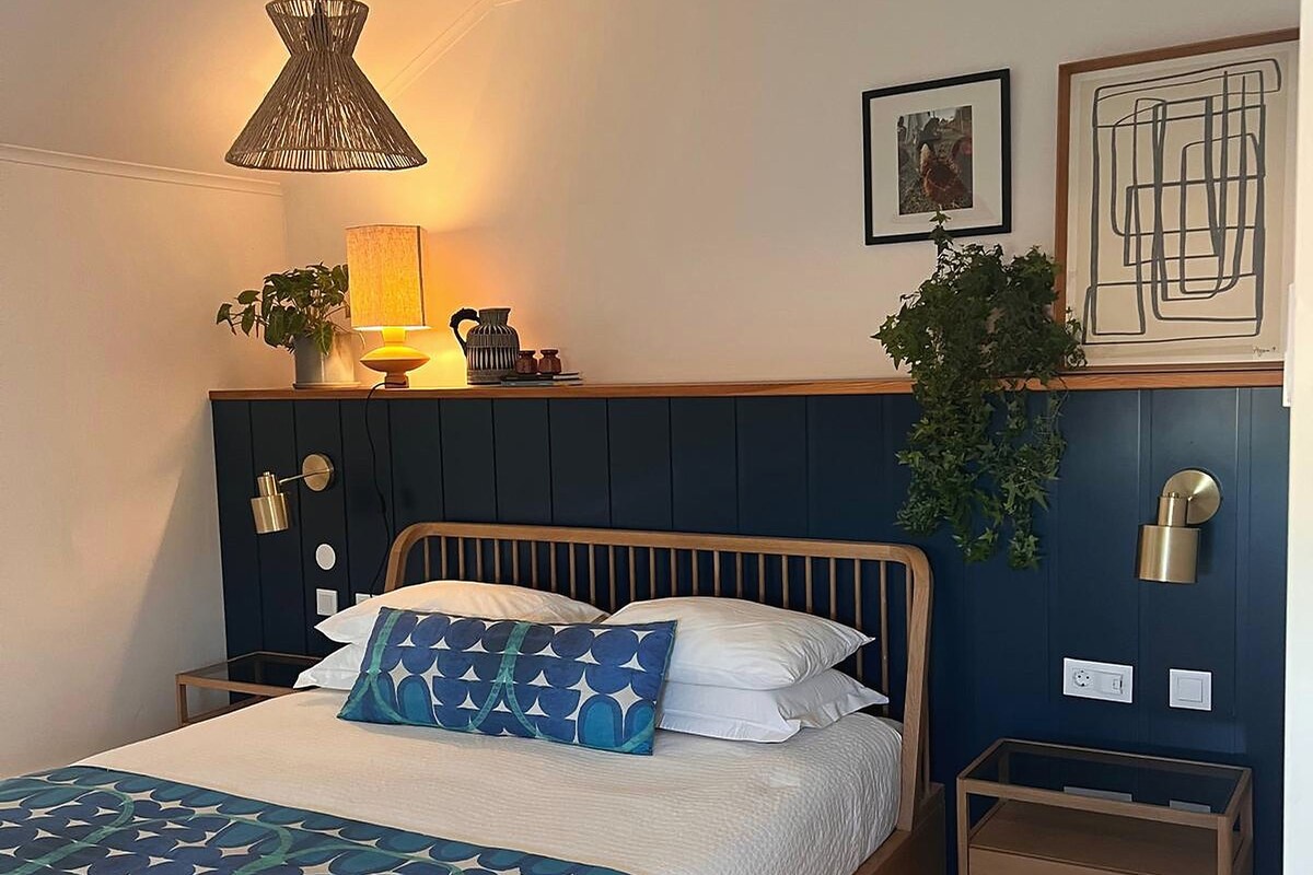 A bedroom with a bed, bedside tables, a lamp, and wall art.