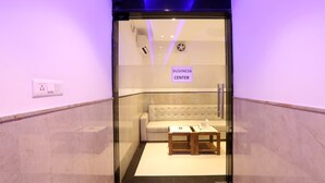A business center with a sofa and two tables, a sign indicating the area, and a glass door. - Hotel Arch Suites (New Delhi)