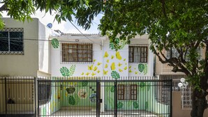 A residential building with a gated entrance, green foliage, and a satellite dish. - Macondo Hostel (Santa Marta)