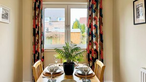 A dining area with a table set for two, a potted plant, and a view of the outside. - 3 bedroom accommodation in Ceres, near Cupar (Ceres, near Cupar)