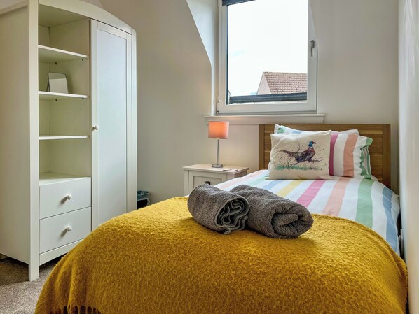 A bedroom with a bed, a wardrobe, a nightstand, a lamp, and a window. - 3 bedroom accommodation in Ceres, near Cupar (Ceres, near Cupar)