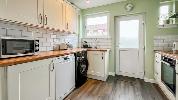 A compact kitchen with white cabinetry, a microwave, a toaster, a washing machine, and a sink. - 3 bedroom accommodation in Ceres, near Cupar (Ceres, near Cupar)