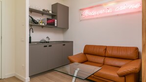 A modern kitchen with grey cabinets, a glass-top table, and a neon sign. - Nice studio 100 meters from Plaza de Callao (Madrid)
