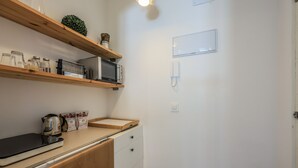 Et køkken med træhylder, en mikrobølgeovn, en elkedel og en kaffemaskine.