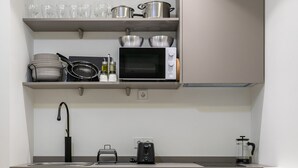 Een kleine keuken met een magnetron, waterkoker en koffiezetapparaat.