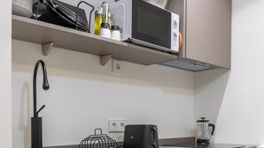 Een moderne keuken met grijze kastjes, een roestvrijstalen spoelbak, een magnetron en een waterkoker.