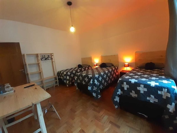 A room with three beds, a wooden table, and a ladder. - Quarto Retrô (São Paulo)
