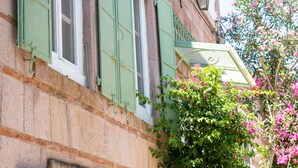 En bygning med grønne skodder, et synligt vindue og en lille balkon med blomsterkasse.