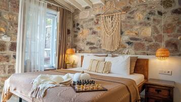 Un dormitorio con pared de piedra, una cama con cabecera de madera, un tablero de ajedrez y un tapiz de macramé.