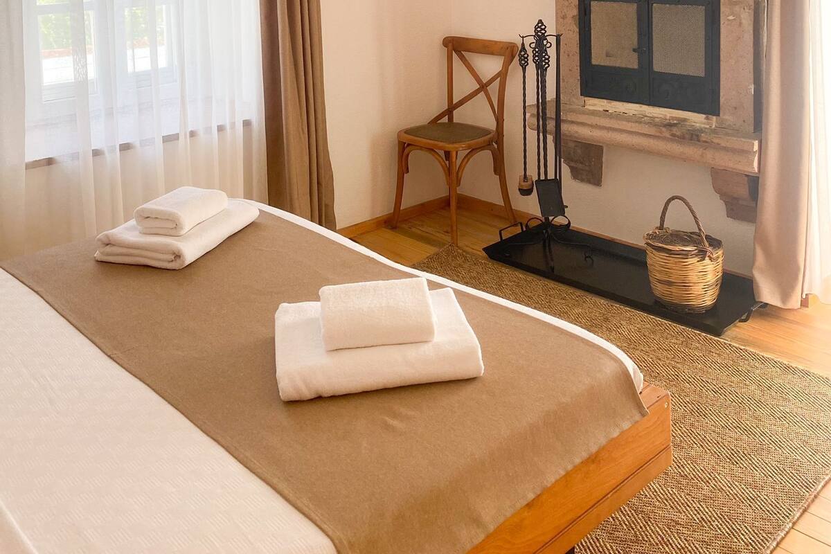 Une chambre à coucher avec un lit, un luminaire suspendu, une cheminée et un tableau au mur.