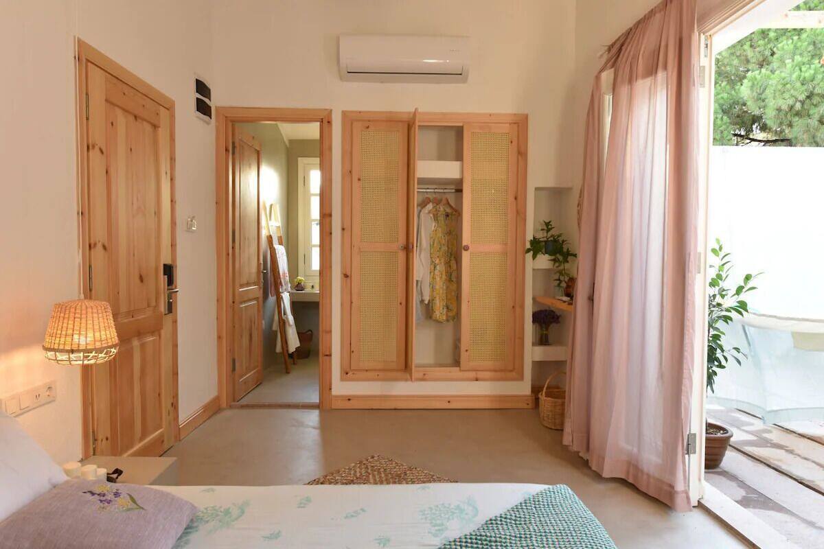 Une pièce comprenant un lit, une armoire, une porte donnant sur un couloir et une fenêtre avec des rideaux.
