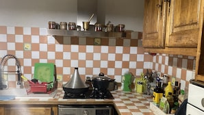 Een keuken met een wasmachine, een fornuis en diverse keukenbenodigdheden op het aanrecht.