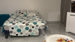 Een slaapkamer met een bed, een klein tafeltje met speelgoed, een stoel en een kast.