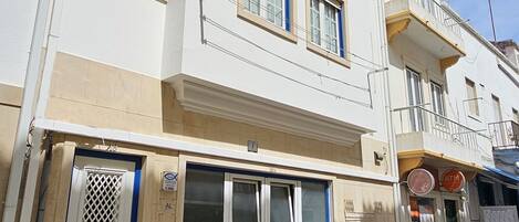 A white building with multiple windows and a ground-floor shop.