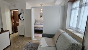 A compact bedroom with a bed, a sofa, a small table, and a wardrobe. -  Sunao (Nazaré)
