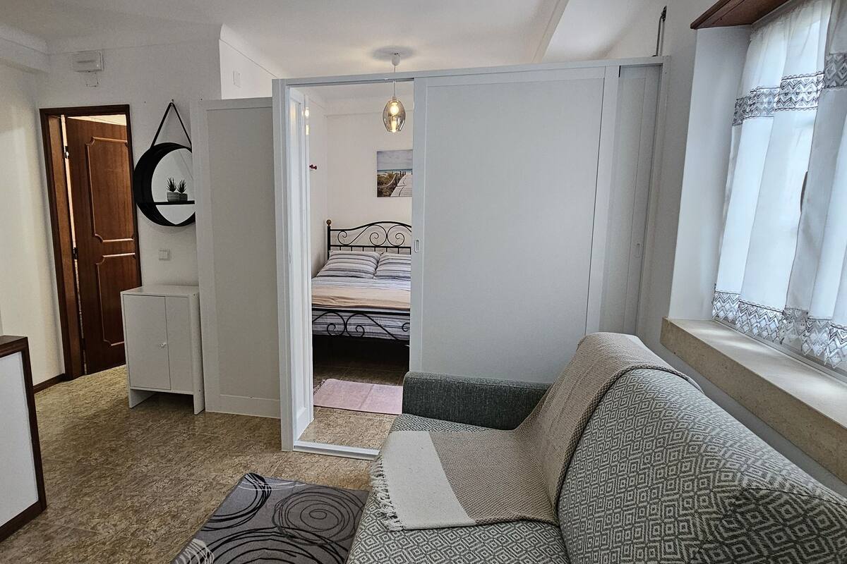 A compact bedroom with a bed, a sofa, a small table, and a wardrobe.