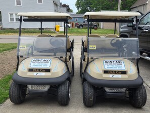 Two golf carts labeled 'RENT ME!' with contact information for TIS Time Rentals in Conn.