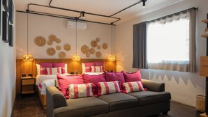 A modern bedroom with a bed, a sofa, decorative wall art, and a window with curtains. - Casa Rosamate (Oaxaca)