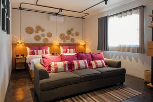 A modern bedroom with a bed, a sofa, decorative wall art, and a window with curtains.
