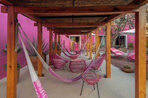 A covered outdoor seating area with hammocks, chairs, and potted plants. - Casa Rosamate (Oaxaca)