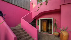 A pink staircase leading to a door, a potted plant, and a tiled floor. - Casa Rosamate (Oaxaca)