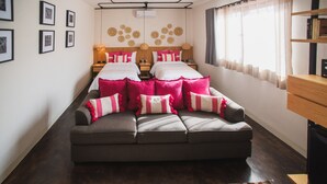 A modern bedroom with a large sofa bed, a wooden headboard, and a striped rug. - Casa Rosamate (Oaxaca)