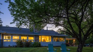 Ein Haus mit einer Veranda, zwei Stühlen und einem großen Baum.
