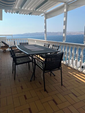 Enjoy al fresco dining or socializing on this shaded terrace overlooking a serene body of water.