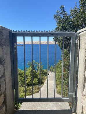 Leading to a scenic coastal path, this property's entrance features a charming metal gate set against a stunning backdrop.