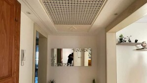 En hall med en trädörr, en spegel och två krukväxter.