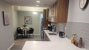 Una cocina moderna con una isla grande, armarios de madera y un comedor con mesa y sillas.