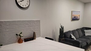 Una cocina moderna con encimera blanca, un reloj en la pared y un revoque de ladrillo gris.