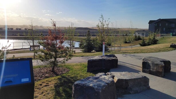Un área de estacionamiento con grandes rocas, un sendero y vistas de un edificio y el paisaje.
