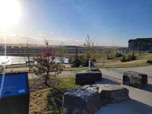 A parking area with large rocks, a pathway, and a view of a building and landscape.