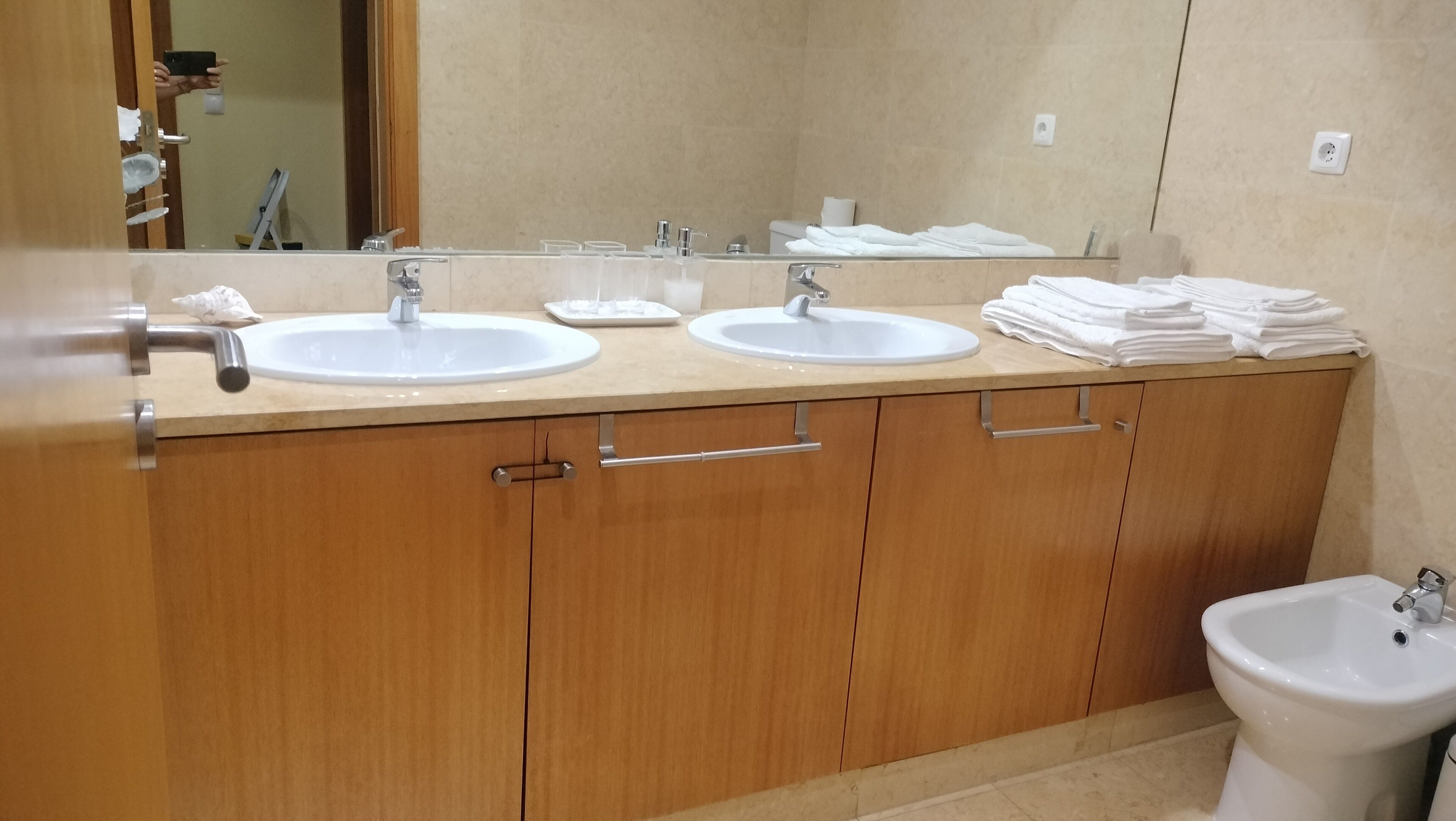 A bathroom with two sinks, a mirror, and a bidet.