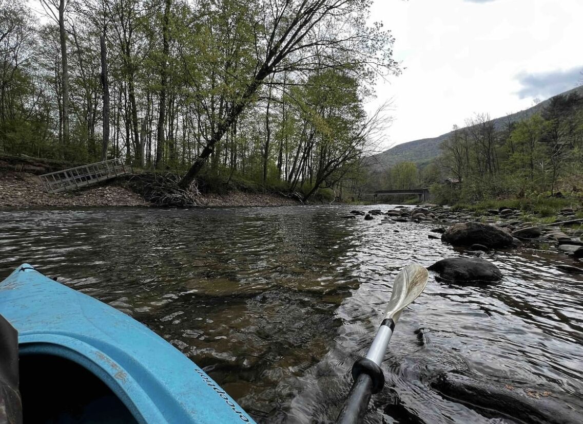 A river with a bridge and a kayak.