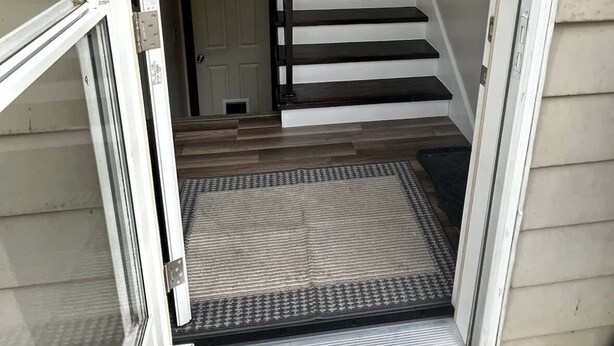 Una escalera que lleva a un piso superior, con una puerta abajo y un enchufe en la pared.