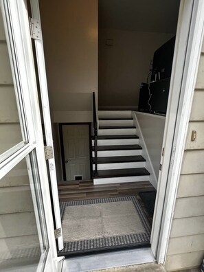 Un escalier menant à l’étage supérieur, avec une porte en bas et une prise de courant sur le mur.