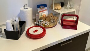 A kitchen counter with a paper towel roll, a bag of bread, a tray of bread, a red tray, and a coffee machine. - 1 Bedroom Villa in Noicattaro (Noicattaro)
