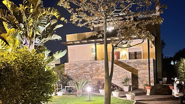 A modern building with a stone facade, a paved entrance, and a well-lit garden area with various plants. - 1 Bedroom Villa in Noicattaro (Noicattaro)