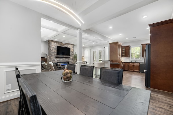 A spacious dining area with a large wooden table, surrounded by chairs, and a stone fireplace. - 4500 sq ft. Cozy/Luxe Mountain style retreat in South CLT- 2 King Masters! (Weddington)