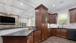 Una cocina moderna con armarios de madera, encimera negra y salpicadero de piedra.