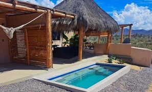 A pool area with a thatched-roof structure, wooden pergola, and a view of the desert landscape. - Private Villa • Heated Pool • Ocean Views • Wal to Beach (El Pescadero)